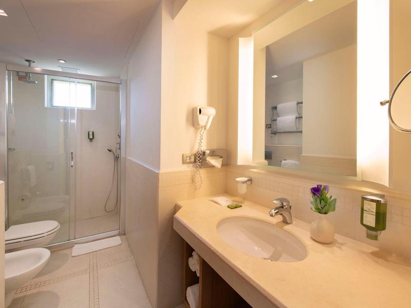 Helles, modernes Badezimmer mit Waschbecken, Spiegel und begehbarer Dusche.