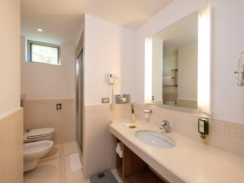 Modernes Hotelbadezimmer mit Bidet, WC und großem beleuchtetem Spiegel.