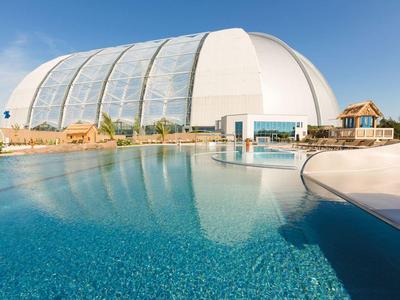 Großes, rundes Tropenhaus mit Pool und klarem blauen Himmel im Hintergrund