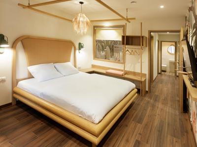 Modernes Hotelzimmer mit Holzboden, großem Bett und warmem Beleuchtungskonzept.