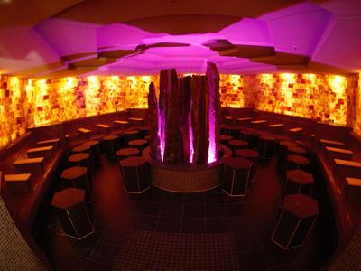 Inneres eines stilvollen, runden Wellnessbereichs mit gedämpftem orange-rosafarbenem Licht.