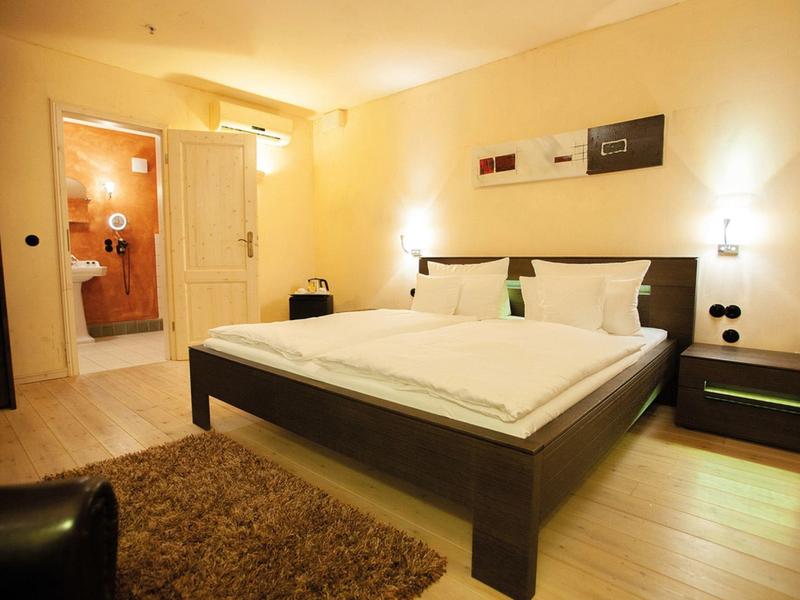 Modernes Hotelzimmer mit Doppelbett, Nachttisch und angrenzendem Badezimmer.