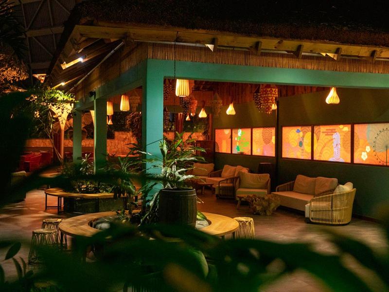 Gemütliche, beleuchtete Lounge im Freien mit Sofas und Pflanzen in einem Hotel