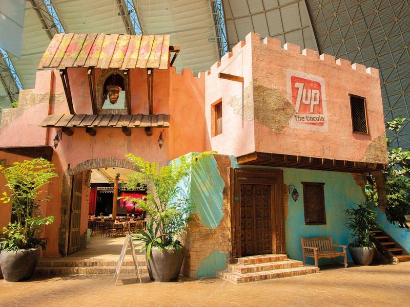 Buntes zweistöckiges Gebäude mit Pflanzen vor dem Eingang in sonniger Umgebung