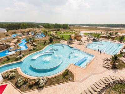 Großes Außenpoolgelände mit Wasserrutschen und Sonnenliegen in einer Urlaubsanlage.