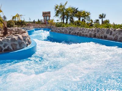 River with fast-flowing water at a tropical resort under a blue sky.