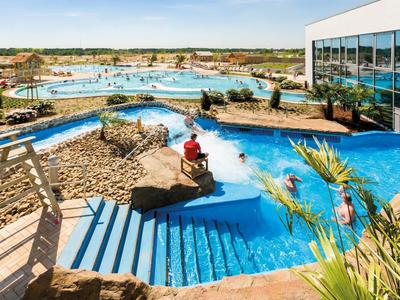 Leisure center with water slides, pools, and people on a sunny day