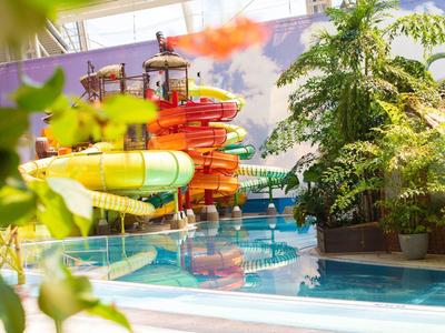 Colorful water slide paradise in an indoor water park with a clear glass roof.