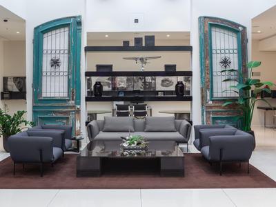 Modern eingerichteter Hotel-Loungebereich mit grauen Sofas, Glastisch und dekorativen grünen Türen.