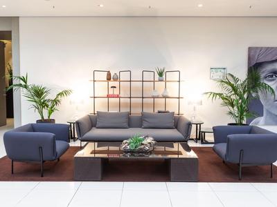 Moderner Lounge-Bereich mit blauem Sofa, Sesseln, Pflanzen und dekorativem Wandbild in einem Hotel