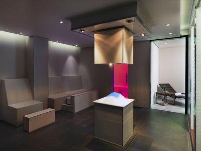 Área de bienestar moderna con tumbonas de sauna y estufa escultórica en ambiente tranquilo.