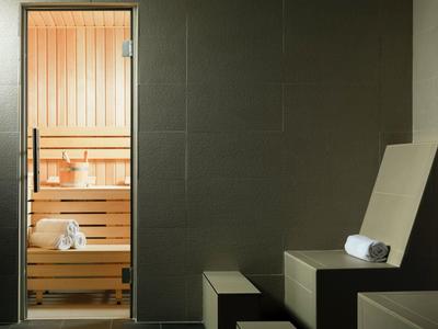 Sala de sauna moderna con banco de madera y tumbona, ambos con toallas dobladas.