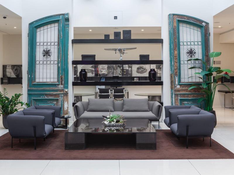 Área de salón acogedora con sofás grises y grandes puertas verdes en el hotel.