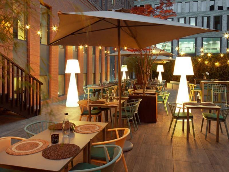 Terraza acogedora de restaurante con mesas de madera, sillas y luz cálida al atardecer.