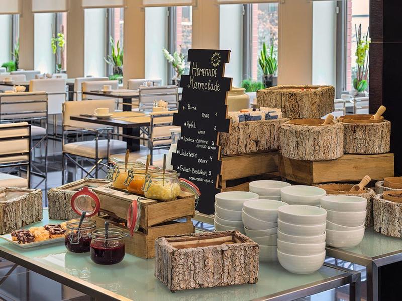 Bar moderna de hotel con cestas, vasos, tazas y una pizarra con especialidades de bebida.