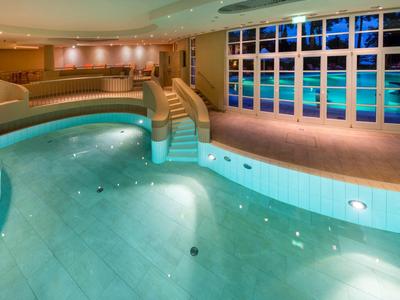 Zona piscina interna con piscina curva e grande parete finestrata