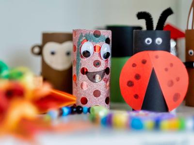 Colorful handmade insect figures made from toilet paper rolls on a table.