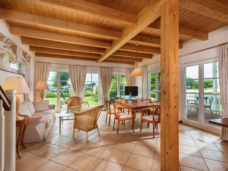 Bright living room with wooden beams, terracotta floor, cozy seating, and terrace view.