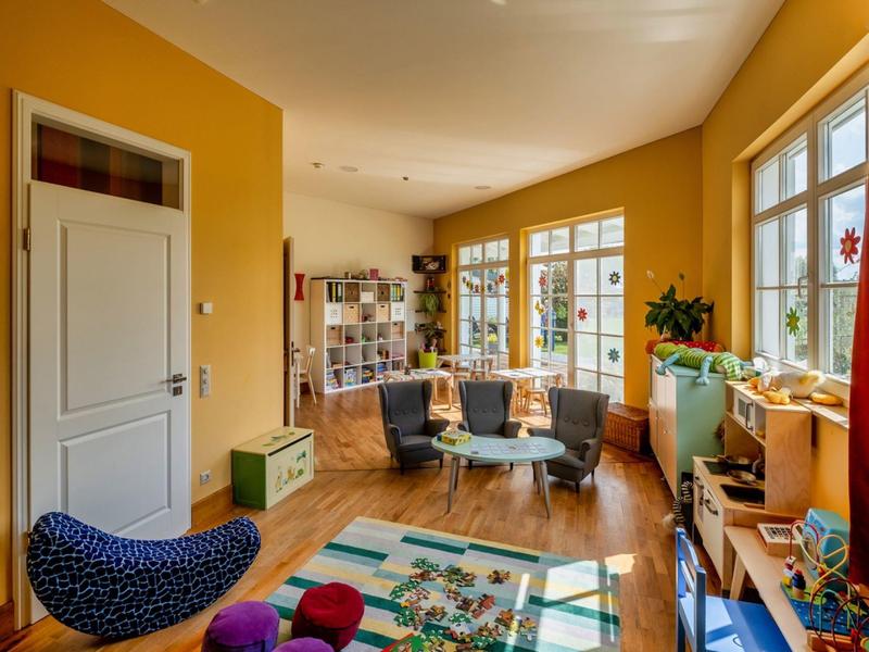 Cozy, bright living room with large windows, colorful rug, and comfortable armchairs.