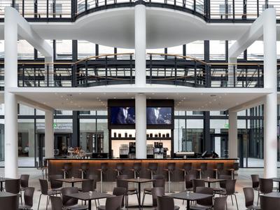 Modernes Bar- und Sitzbereich im Hotel mit klaren Linien und monochromer Farbpalette.