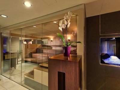 Espace sauna moderne avec bancs en bois et murs en verre, décoré avec une orchidée.