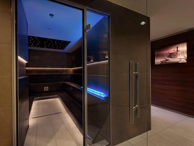 Sauna moderne avec bancs en bois, façade en verre et éclairage tamisé dans un intérieur d'hôtel