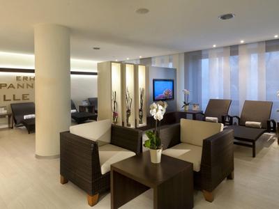 Salon d'hôtel moderne et lumineux avec des fauteuils et des tables confortables.