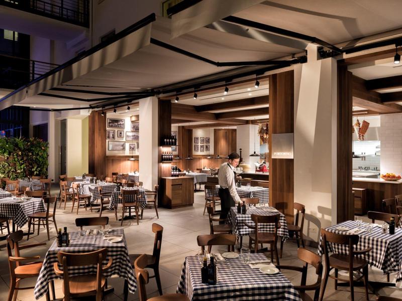 Restaurant confortable avec nappes à carreaux et tables dressées sous un éclairage chaleureux du soir.