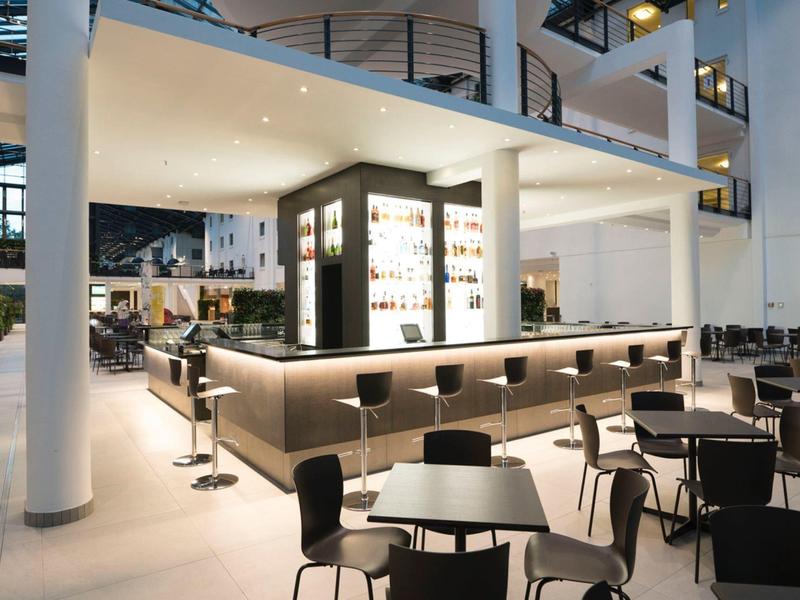 Zone de bar d'hôtel moderne avec sièges élégants et éclairage sophistiqué.