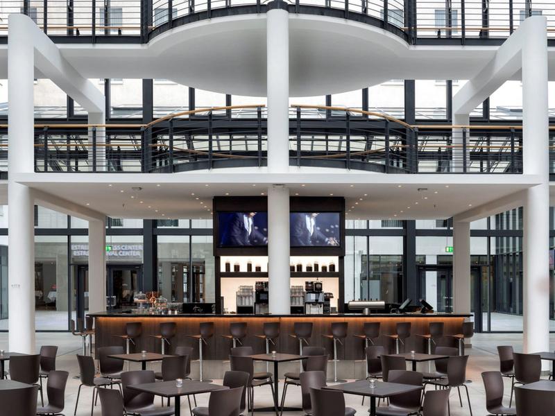 Hall d'hôtel moderne avec bar et de nombreuses chaises dans une grande pièce lumineuse.