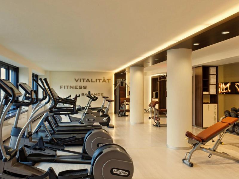 Salle de sport moderne avec appareils cardio et zone de musculation dans un hôtel.