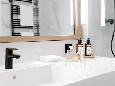 Moderner Hotelwaschbecken mit Handtüchern und Pflegeprodukten, heller Marmorhintergrund.