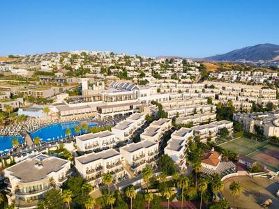 Uitgestrekt hotelcomplex op de heuvel met zwembaden en palmbomen onder een blauwe lucht
