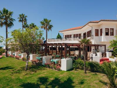 Hotelcomplex met terras, tuin en palmbomen bij zonnig weer