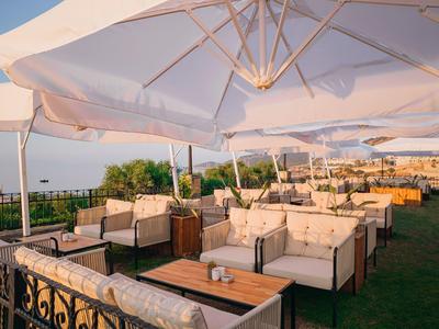 Gezellige buitenzitplaatsen met wit beklede meubels en grote parasols op gras.