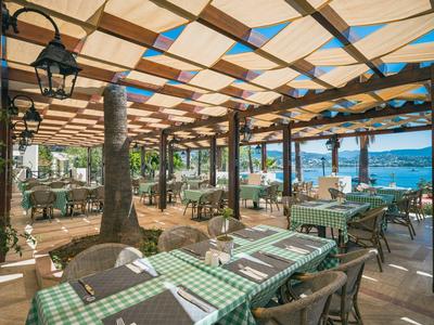Open buitenrestaurant met groen geruite tafelkleden en uitzicht op zee.