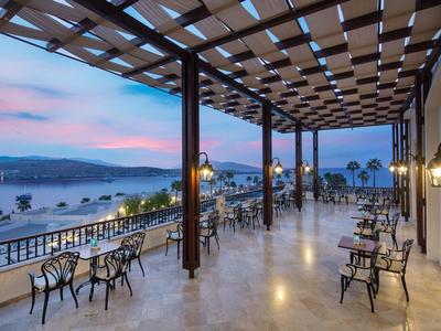 Grande terrazza dell'hotel con posti a sedere e vista sul mare al tramonto.