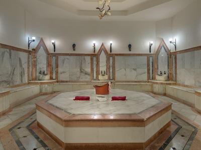 Grote ronde spa-ruimte met marmeren bad en spiegelwanden in een wellnesshotel.