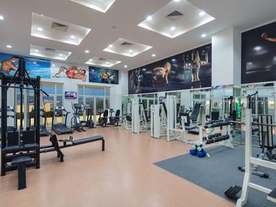 Moderner Fitnessraum mit verschiedenen Trainingsgeräten und Spiegelwänden.