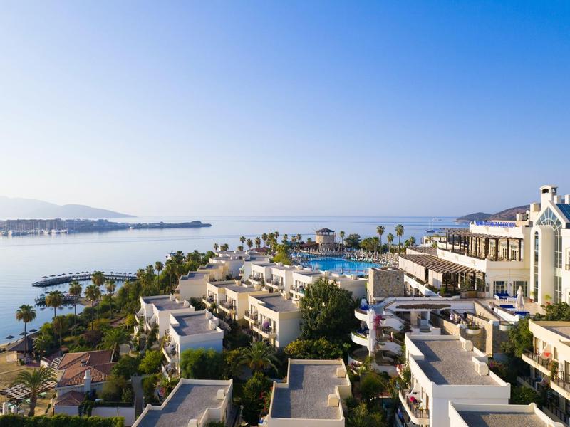 Luxe hotelresort met zwembad aan zee onder heldere blauwe lucht