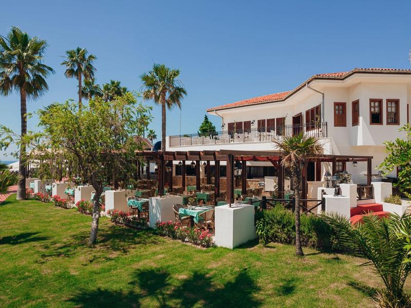 Hotelcomplex met terras, tuin en palmbomen bij zonnig weer