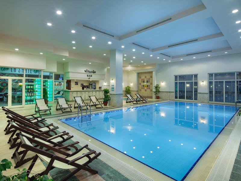 Goed verlicht binnenzwembad met ligstoelen en grote ramen in een hotel.