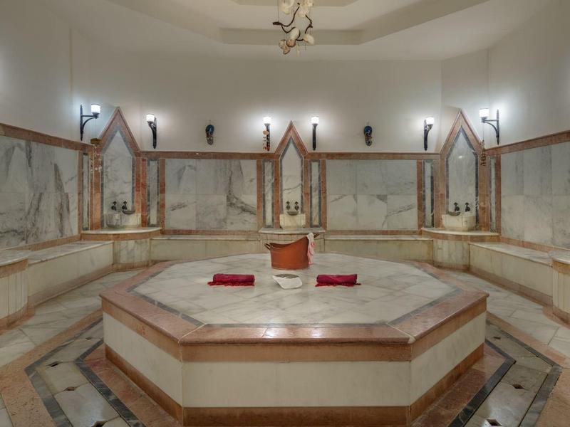 Grote ronde spa-ruimte met marmeren bad en spiegelwanden in een wellnesshotel.