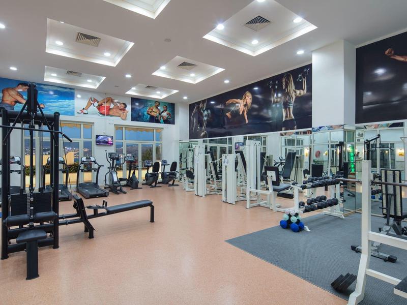 Moderne sportschool met diverse fitnessapparaten en grote spiegels aan de muren.