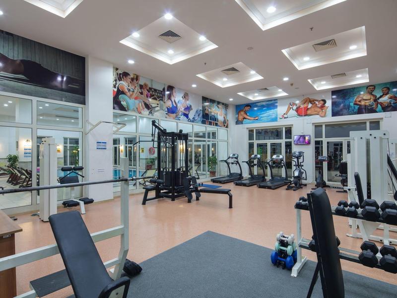 Moderne fitnessruimte met diverse trainingsapparatuur en spiegelwanden.