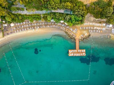 Aerial view of a beach with sun loungers and a pier over turquoise water