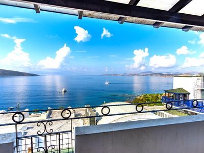 Blick von einem Balkon auf das blaue Meer und den Strand bei klarem Himmel.