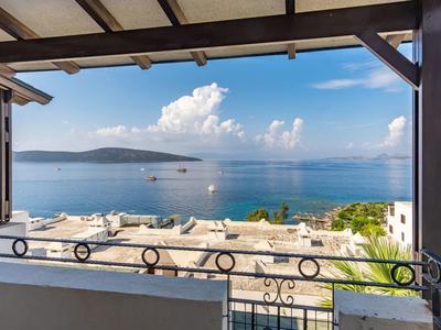 View of the sea from a covered terrace with beams and railing.