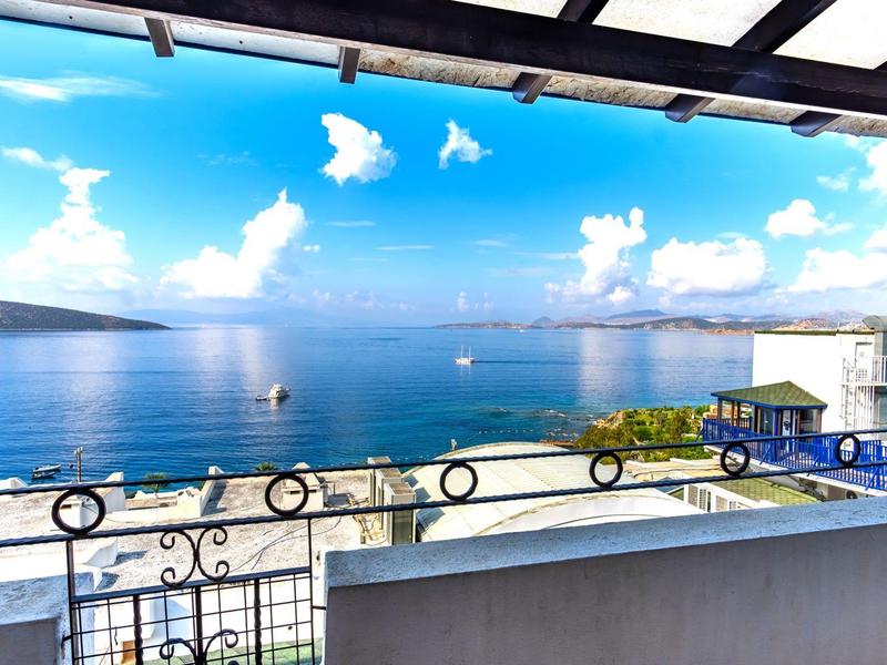 View from a balcony overlooking the sea with clear sky and scattered clouds.