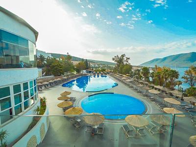 Piscine d'hôtel moderne avec parasols surplombant un paysage vallonné et un lac